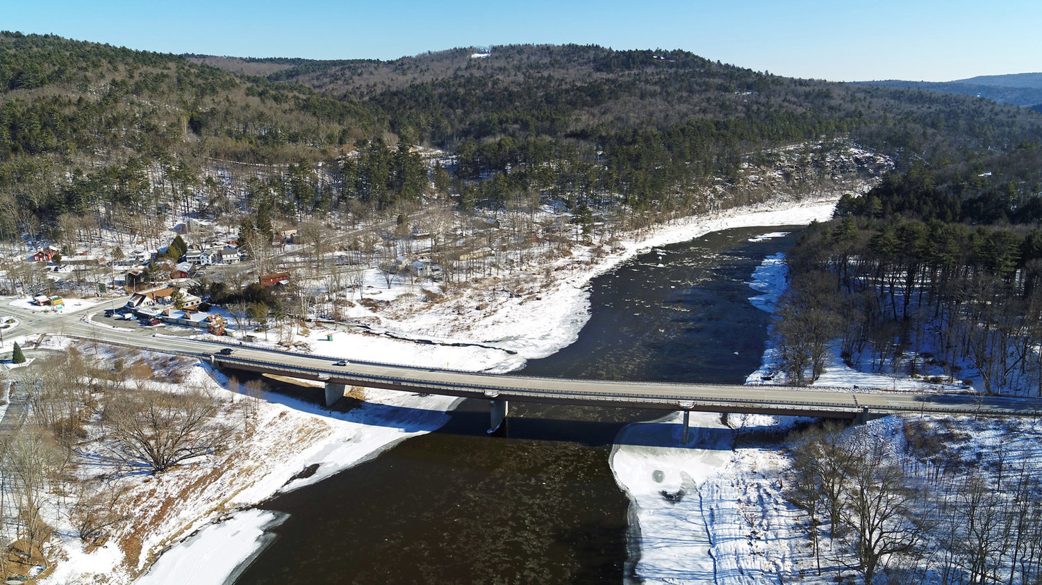 This aerial photo looks downstream and shows the Shohola rapids—or Shohola rift as denoted on some maps—just below the Shohola-Barryville bridge. Halfway Brook is just past the bridge and the river on the left, on the New York side. Some sheet ice is evident on both shores; it looks solid, but several thin spots can be seen.